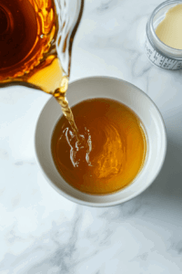 This image shows cream being poured into the saucepan to start the sauce.
