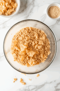 This image shows crushed pork rinds being added as a crispy topping.