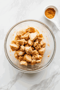 This image shows diced chicken being mixed with marinade ingredients