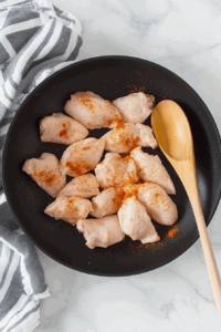This image shows chicken breasts sizzling in the skillet as they cook.