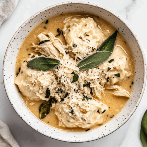 This image shows a bowl of keto chicken dumplings garnished with fresh herbs. ready to be served for dinners and lunches