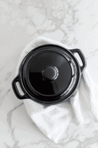 placing-a-towel-over-the-crockpot-and-covering-with-the-lid so the chocolate melts with even heat