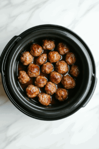 placing-pre-cooked-meatballs-in-the-slow-cooker neatly so that they absorb sauce equally