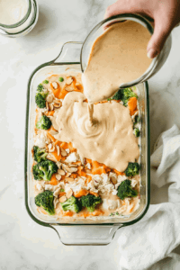 This image shows the creamy cheese sauce being poured over the layered chicken.