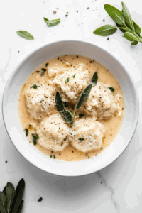 This image shows a bowl of keto chicken dumplings garnished with fresh herbs.