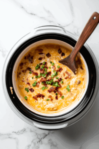 This image shows shredded cheddar cheese, bacon bits, and green onions stirred into the mixture