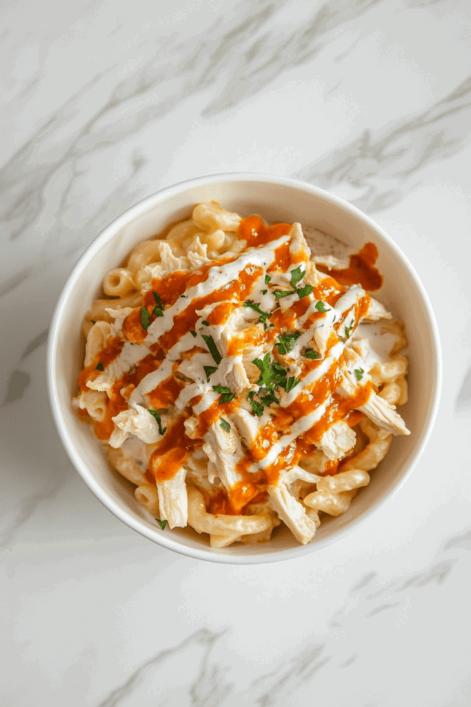 buffalo-mac-and-cheese-served-in-a-bowl-with-red-sauce-and-cilantro-garnish