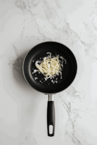 This image shows onions being sautéed with kosher salt in the pan.