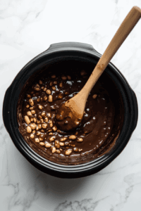 stirring-the-melted-chocolate-in-crockpot to let the peanuts cover chocolate properly