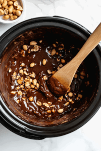 white-chocolate-peanuts-chocolate-chips-and-german-chocolate-in-a-crockpot-being-cooked-on-high-flame and stirring every 15 minutes