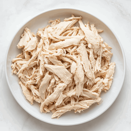 This image shows a top-down view of shredded 2 Ingredient Vegan Chicken presented on a white round plate, ready to enjoy or use in various dishes.