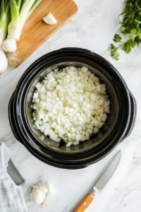 this image shows crockpot base is prepared with a generous layer of caramelized onions, creating a flavorful foundation for the whole chicken.