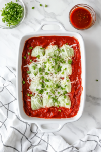 This image shows a ladle pouring marinara sauce over the stuffed cabbage rolls, evenly coating them.