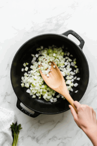 Adding minced garlic to the pot for vegan broccoli cheese soup Alt Text: This image shows minced garlic being added to the sautéed onions and celery, enhancing the savory aroma of the vegan broccoli cheese soup.