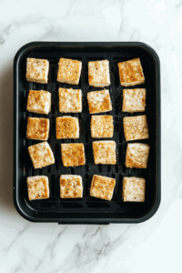This image features breaded tofu strips neatly placed on an air fryer tray, ready for cooking to crispy perfection.