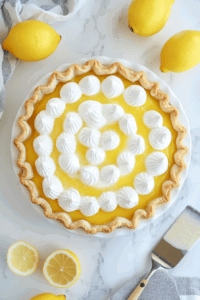 This image shows the process of layering tangy lemon curd and whipped aquafaba meringue over the cooled pie crust, assembling the vegan lemon meringue pie.