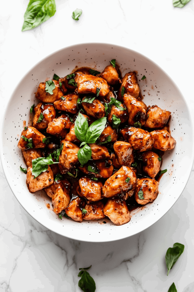 this image shows juicy balsamic chicken, slow-cooked to perfection and garnished with fresh basil leaves and cilantro.