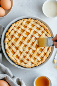 This image shows a fine layer of powdered sugar being sprinkled over the baked Vegan Linzer Torte, giving it a festive and classic final touch.
