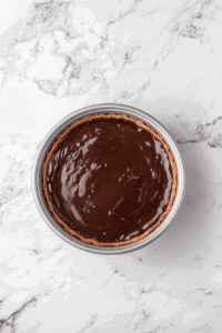 This image shows the prepared vegan chocolate tart being placed in the refrigerator, allowing the smooth chocolate filling to set firmly.