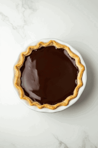 this image shows The pie is refrigerated to allow the chocolate filling to set firmly before adding the meringue topping.