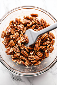 This image shows chopped pecans being gently folded into the pecan filling mixture in a mixing bowl.