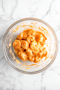 This image shows air-fried shrimp being coated in the creamy Bang Bang sauce, ensuring each piece is evenly covered.