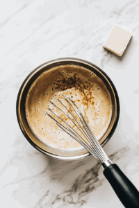 This image shows lemon curd being whisked and cooked in a saucepan, creating a smooth and tangy filling for the vegan lemon meringue pie.