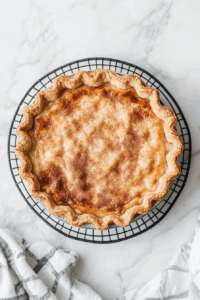 This image shows the Vegan Sugar Cream Pie cooling on a countertop after baking, allowing the flavors to settle before chilling.