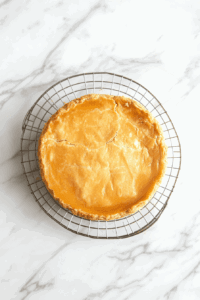This image shows the freshly baked vegan pumpkin pie resting on a wire rack, cooling completely before being refrigerated to set its texture.