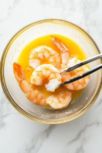 This image shows a shrimp being dipped into the beaten egg, ensuring it is fully coated before moving to the crumb mixture.