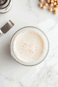 This image shows chickpeas being drained to extract the liquid, which will be used to create a creamy vegan whipped cream.