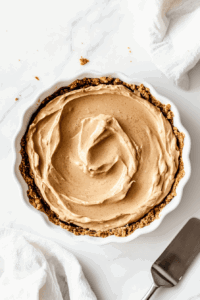 This image shows the creamy coconut milk mixture being poured into the partially baked pie crust, filling it to create a smooth and luscious pie.