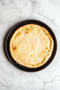 This image shows the finished fathead pizza crust, baked to a golden-brown perfection, ready for toppings to be added.