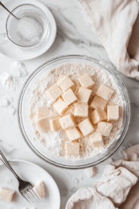 This image shows a clean workspace with pie crust ingredients such as flour, vegan butter, and a mixing bowl, ready to be combined into dough.