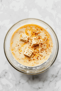 This image shows tofu strips being soaked in a vibrant and aromatic marinade to absorb rich flavors.