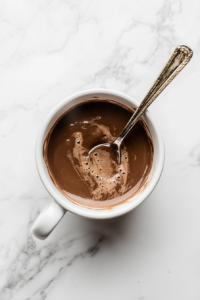 This image shows a spoon stirring the chocolate batter in a mug, combining the wet and dry ingredients until the mixture is smooth and free of lumps.