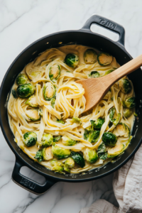 this image shows The sautéed Brussels sprouts and garlic being stirred into the creamy pasta sauce, combining the flavors for a delicious vegan dish.
