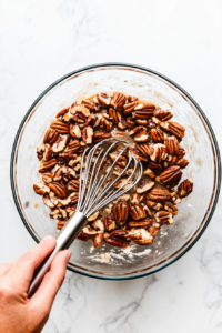This image shows a whisk blending the pecan filling ingredients into a smooth and glossy mixture.