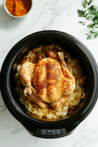 this image shows seasoned whole chicken is gently placed in the crockpot on top of a bed of caramelized onions, ready for slow cooking.
