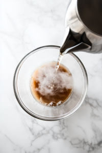 A bowl of chocolate cake batter with boiling water being added to enhance the rich and smooth texture of the batter.