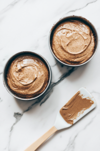 Silky Hershey chocolate cake batter being poured evenly into two prepared baking pans, ready for baking.
