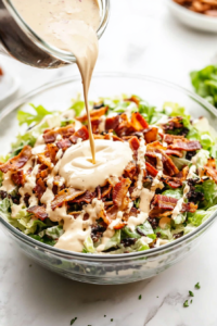 pouring-creamy-dressing-over-the-layered-salad