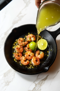 This image shows freshly squeezed lime juice being poured into the pan, combining with sautéed garlic and honey to add a zesty and tangy flavor to the Garlic Honey Lime Shrimp.