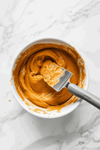 This image shows a smooth, spiced pumpkin filling being poured into the prepared almond butter crust, ready for baking into a vegan and gluten-free pumpkin pie.