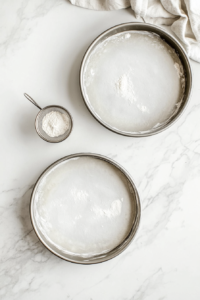 Baking pans lined with parchment paper and lightly greased, ready for the rich chocolate cake batter.