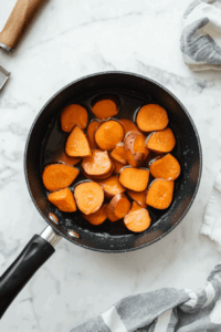 This image shows peeled and chopped sweet potatoes on a cutting board, ready to be boiled for the pie filling.