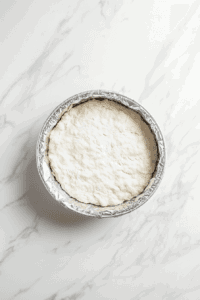 This image shows the pastry dough being pressed into the tart pan, ready to be pre-baked, forming the crust for the Vegan Treacle Tart.