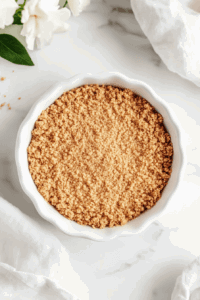 this image shows The crust mixture is pressed evenly into a pie pan, forming the base for the Vegan Chocolate Meringue Pie.