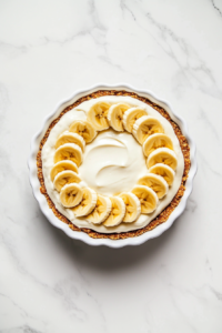 This image shows a fully assembled vegan banana cream pie placed in the refrigerator to chill and set before serving.