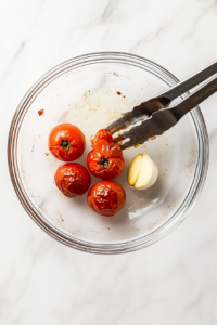 This image shows the process of removing roasted vegetables and shrimp from the sheet pan, leaving the crispy pepperoni and the pan juices behind.